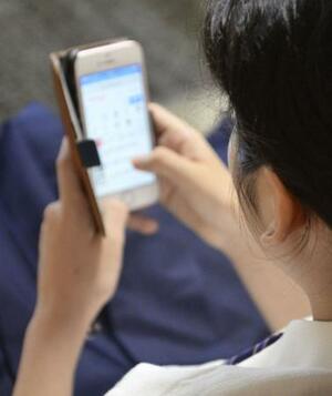 スマートフォンを操作する人=東京都内