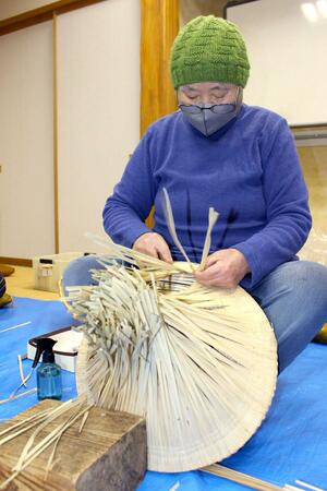 スゲを笠骨に丁寧に縫い付けていく佐藤タカ子さん＝佐渡市秋津