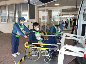 特別養護老人ホームの要支援者役を福祉車両から降ろす、防災訓練の参加者＝９日、村上市