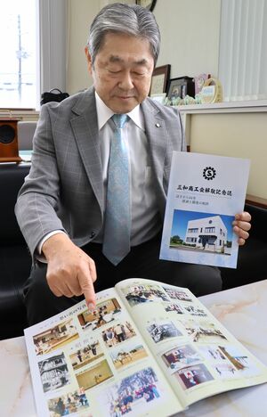 記念誌を手に三和商工会の歴史を振り返る西山薫会長=上越市三和区