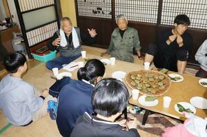 生椿集落の歴史などについて、団子を食べながら語り合う参加者ら=佐渡市生椿地区