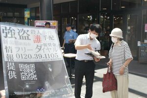 2009年に発生した強盗殺人事件を巡る情報提供を市民に呼びかける警察官=29日、新潟市東区