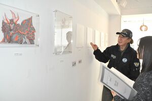 紺吉の初個展で、自身の原画デザインを説明する板野一郎さん(奥)=1月10日、東京・京橋の並樹画廊