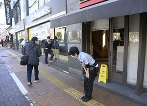モバイルオーダーや対面での注文が受けられない状態が続き、店舗の前で頭を下げるマクドナルドの店員=3月15日午後3時11分、東京都内