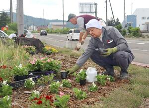 国道交差点の花壇を整備する佐梨地区コミュニティ協議会のメンバーら=5月25日、新潟県魚沼市中原