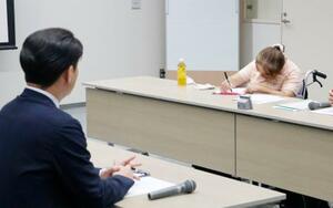 トライグループの現地研修で「子どもたちに正確に伝えてほしい」と筆談で訴えた、胎児性水俣病患者の古山知恵子さん。手前は阿部正純執行役員=2日午後、新潟市