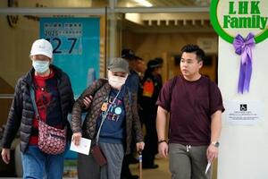 立法会選挙の投票を終え、火災が起きた高層住宅群近くの投票所を出る有権者ら=7日、香港(共同)