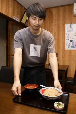 リニューアルした「大阪屋支店」で、一押しメニューのチャーハンを提供する4代目渡邊伊吹さん=田上町吉田新田