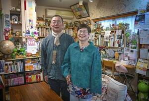 自身が営む喫茶店「・オリーブガーデン・」で藤井幸之助と手をつなぐ藤岡美千代。幼い頃、近所の家で読んだ本に描かれていたカエルの絵に心が温かくなった。「幸せの象徴」として店のあちこちに置いている=2025年5月、大阪市東淀川区(撮影・今里彰利)