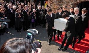 出棺のため関係者に運ばれる仲代達矢さんのひつぎ。参列する役所広司さん(左奥)の姿もあった=14日午後、東京都世田谷区