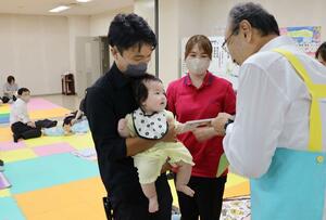 赤ちゃんへ絵本をプレゼントする渡辺竜五市長=佐渡市河原田本町