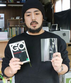 「BOOKSKIN」を紹介するいづみ商会社長の安達拓未さん。左は文庫本を入れた状態=三条市西四日町3