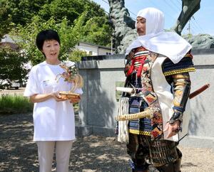 越後上越上杉おもてなし武将隊にスゲ細工「馬上謙信」を贈った柴野美佐代さん(左)=上越市春日山町1