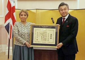表彰状を持つマクドナルド昭子さん(左)と鈴木浩駐英国大使=19日、ロンドン(共同)