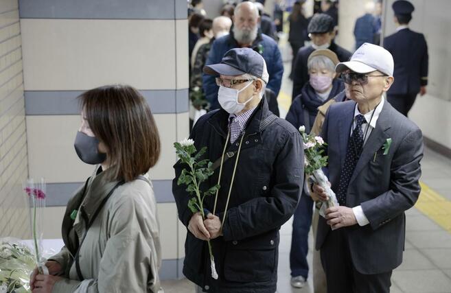 地下鉄サリン事件から３０年となり、東京メトロ霞ケ関駅に設けられた献花台に並ぶ人たち＝３月２０日、東京都千代田区