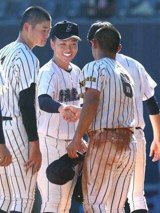 新潟産大付-帝京長岡 試合を終え、健闘をたたえ合う新潟産大付のエース小平乃希(中央)と帝京長岡の主将山野陽(右)=7月24日、新潟市中央区長潟のハードオフ・エコスタジアム