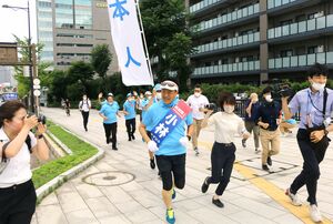 新潟市中心部を走りながら支持を呼びかける小林一大氏(中央)=6月26日、新潟市中央区