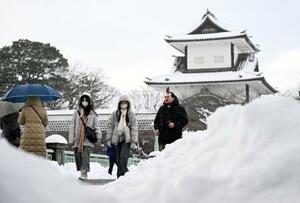 　雪が降り積もる中、金沢市内を歩く人たち＝２２日午後