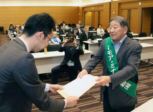 環境省の担当者に、要請書を手渡す新潟水俣病第5次訴訟の皆川栄一原告団長(右)=4月24日、東京・永田町
