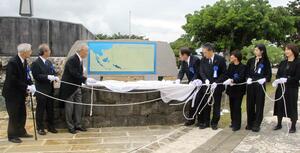 修復した地図入り碑文の除幕式。新潟の塔は同じ敷地内にある=17日、沖縄県糸満市