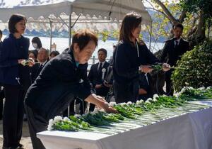 広島県竹原市の大久野島で開かれた慰霊式で、献花する遺族ら=24日午前