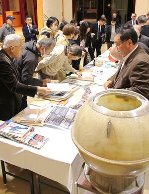 タイムカプセルに入っていた40年前の資料を眺める住民ら=魚沼市堀之内