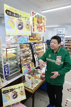 ドーナツ売り場の前で日本一達成の喜びを語る小林勇介さん。見本やポップは従業員が手作りした=新潟市中央区のセブン-イレブン新潟古町通4番町店