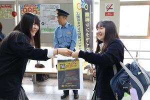防犯広報活動を行った新潟県立新潟向陽高等学校の生徒(左)と、防犯チラシを受け取った高校生(右)=新潟市江南区東船場1