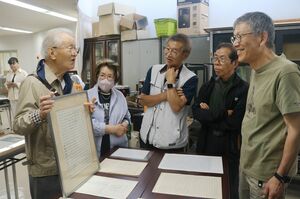 釜田俊雄直筆の楽譜などを眺めて談笑する「みちや会」のメンバーら＝佐渡市石田