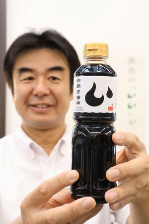 原料の小麦と大豆に弥彦産を100%使用した伊彌彦醤油をPRする竹野勝行さん=弥彦村弥彦