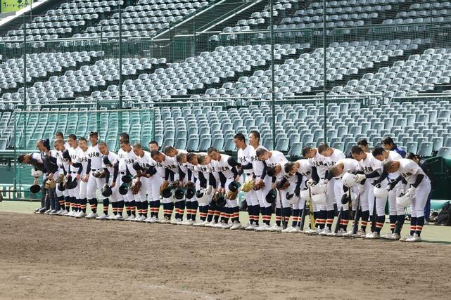 練習開始のサイレンに合わせてグラウンドに向かって頭を下げる日本文理の選手＝甲子園球場