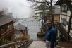 草津温泉の湯畑を指し示す案内人の川口正昭さん=2026年3月、群馬県草津町