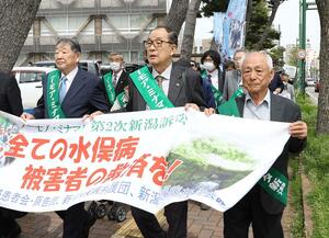 新潟水俣病第5次訴訟で原告らとともに行進する中村洋二郎さん(中央)=2024年4月、新潟市中央区