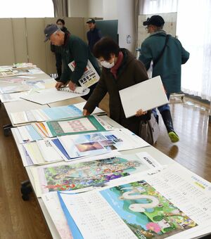 プレゼント会でカレンダーを選ぶ来訪者