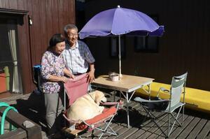 自宅裏のデッキから海を眺める山本正雅さん、利枝さん夫妻と愛犬のメグ=佐渡市相川柴町