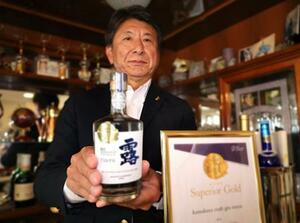 　「鎌倉クラフトジン露」を手にする秋山栄二さん＝１１月、神奈川県逗子市