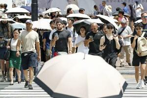 東京・渋谷を歩く人たち。日傘を差す姿が目立った=18日午後