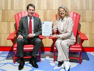 大阪・関西万博のカナダ館に展示されていた「赤い椅子」に座る関西エアポートのブノア・リュロ副社長(左)=13日午前、関西空港