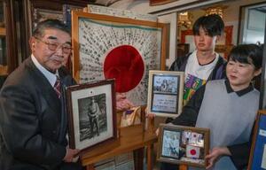 旧日本兵がニューギニアで絶命した時に持っていた日章旗と生前の写真を持つ(左から)佐々木慶一郎、孫の阿部航大、長女の阿部綾=宮城県石巻市