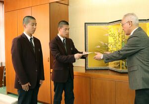 五十嵐裕幸副市長(右)に寄付金を手渡す生徒会長の丸山季煌さん(中央)と鏡真翔さん(左)=加茂市役所