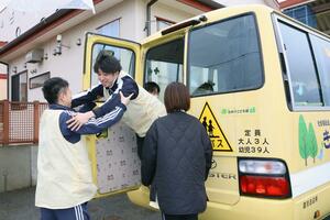 通園バスの緊急脱出ドアの開閉を試すスタッフ=胎内市黒川
