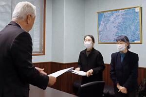 刈羽村の品田宏夫村長(左)に申し入れ書を手渡した原発を再稼働させない柏崎刈羽の会のメンバー=3月29日、刈羽村