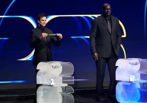 サッカーW杯北中米3カ国大会の組み合わせ抽選で、第1ポットのくじを引くトム・ブレイディさん。右はシャキール・オニールさん=5日、米ワシントン(共同)