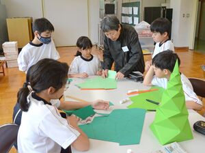 子どもたちに折り紙作品の作り方を教える布施知子さん=津南町上郷宮野原