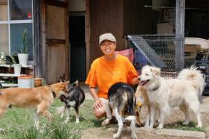 保護犬などに囲まれ笑顔を見せるNPO法人「わんにゃんレスキューOHANA」の松本恵美代表=8日、茨城県神栖市