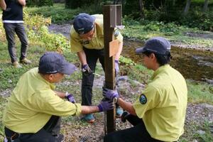 ヒグマ撮影者らの滞留が目立つイワウベツ川付近に監視カメラを設置する環境省職員=12日午後、北海道斜里町