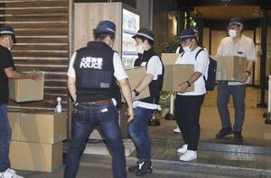 家宅捜索し、段ボール箱を運び出す大阪府警の捜査員ら=7月、大阪市西区