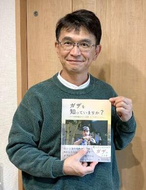 　本「ガザを知っていますか？」を持つ桑山紀彦さん（イマジネイション・プラス提供）