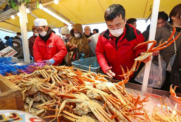 店頭に並んだカニを品定めする買い物客＝３０日、長岡市寺泊下荒町
