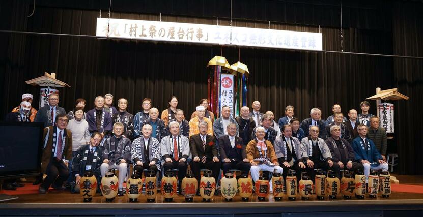 ユネスコ無形文化遺産追加登録を祝い、くす玉の前で記念撮影をする参加者たち=11日、村上市